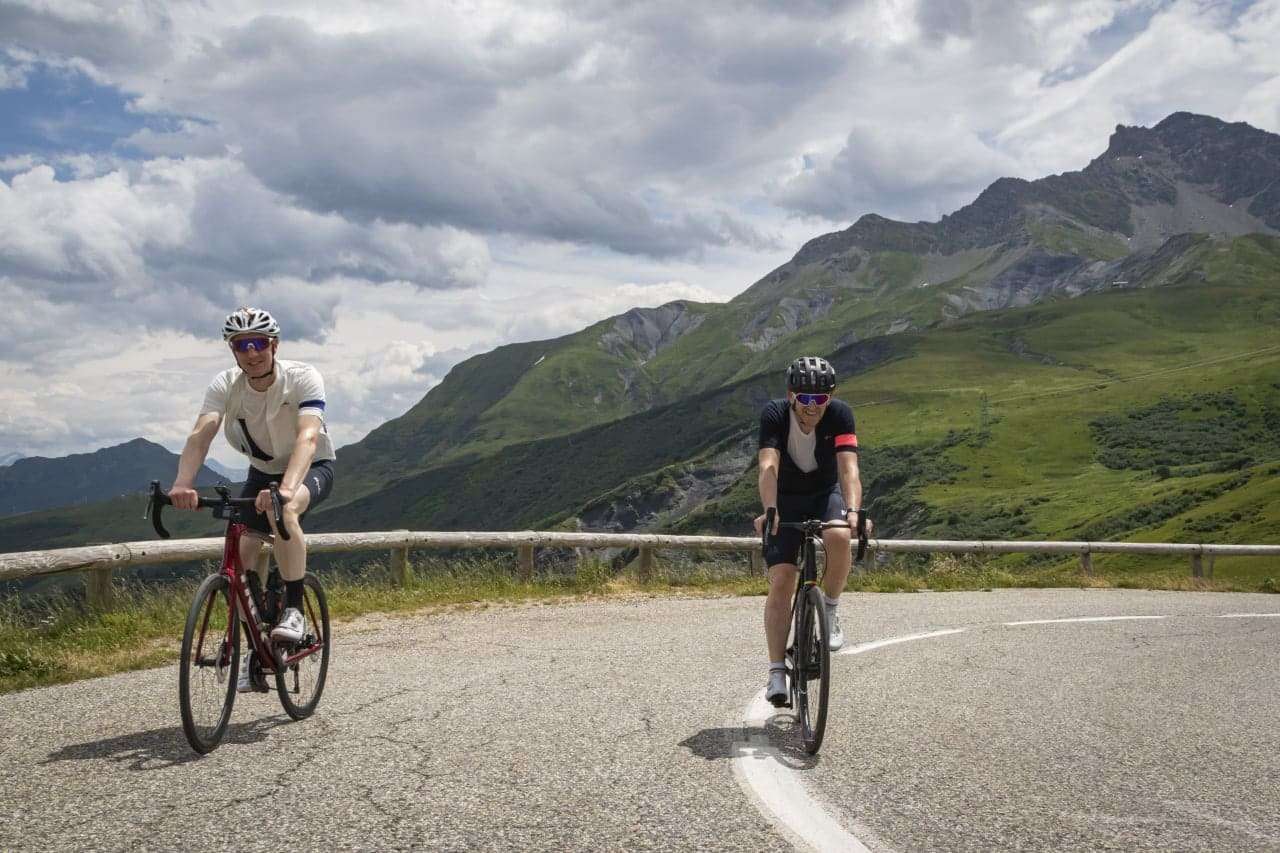 Two cyclists riding up the Col de la Madeleine with mountain view in the background