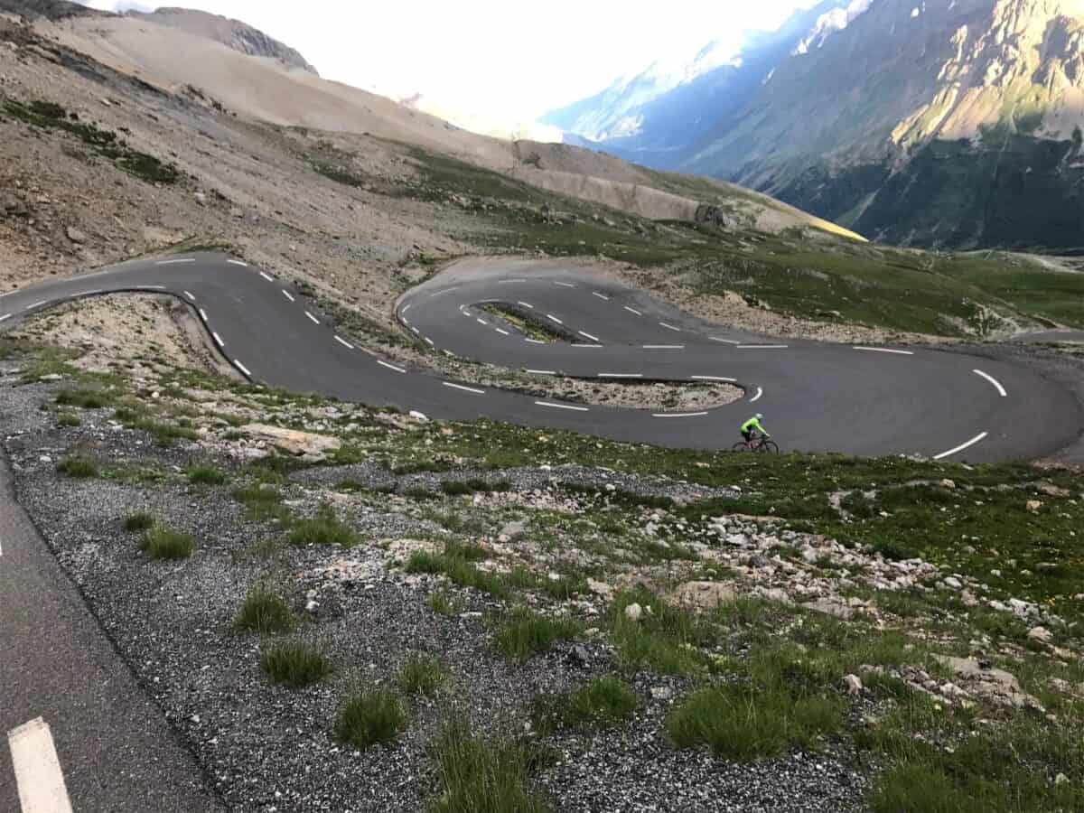 looking down at a cyclist descending through hairpins on col du galibier