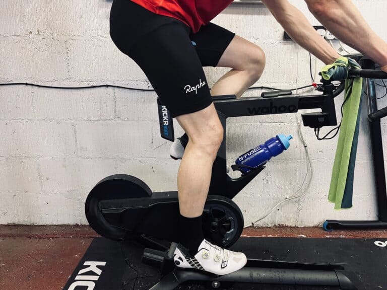 A close up of some cyclist legs on an indoor exercise bike