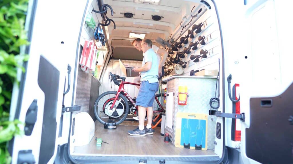 side view of cyclist and bike fitter checking saddle pressure map test results