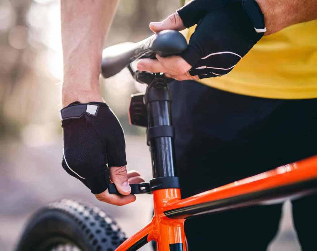 Rider adjusting seat height on bicycle