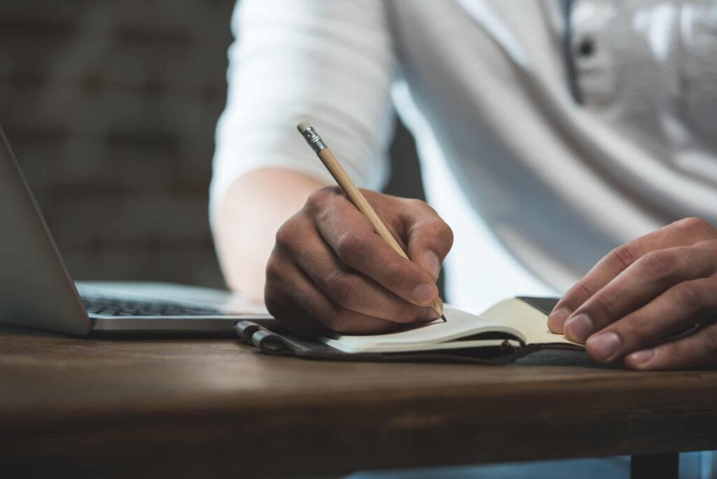 Man writing in notebook his plans