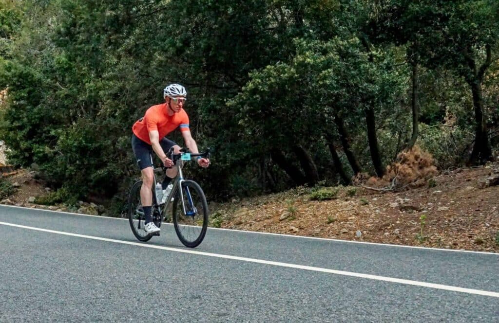 A cyclist endurance training for beginners, riding a bike down a mountain road.