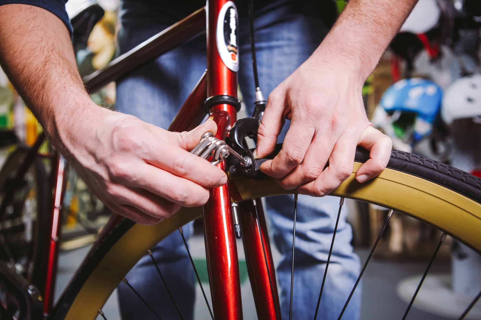 Theme repair bikes. Close up of a Caucasian man’s hand use a hand tool hexagon set to adjust and install Rim Brakes on a red bicycle
