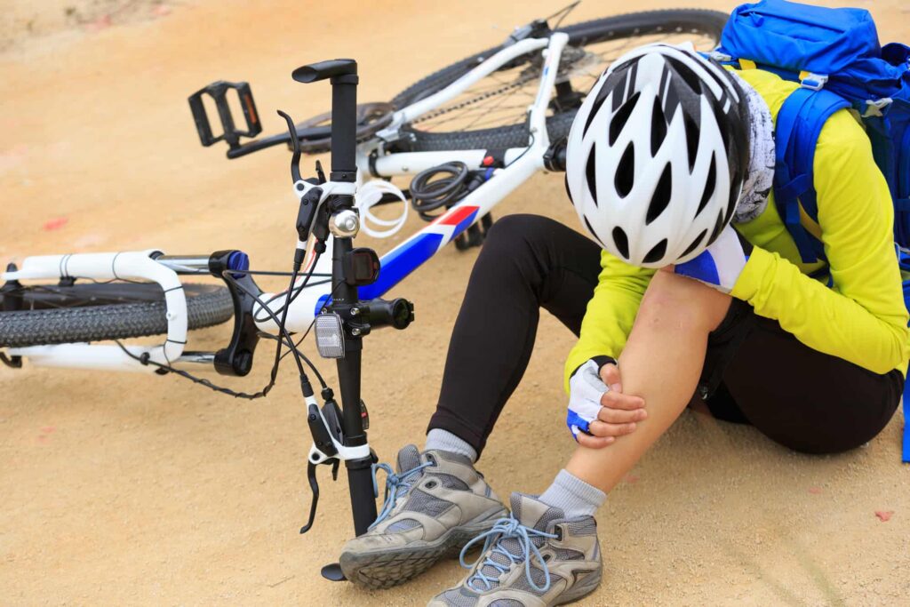 A person sitting on the ground next to a bicycle.