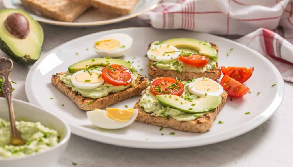 Avocado toast with eggs and tomatoes on a plate.