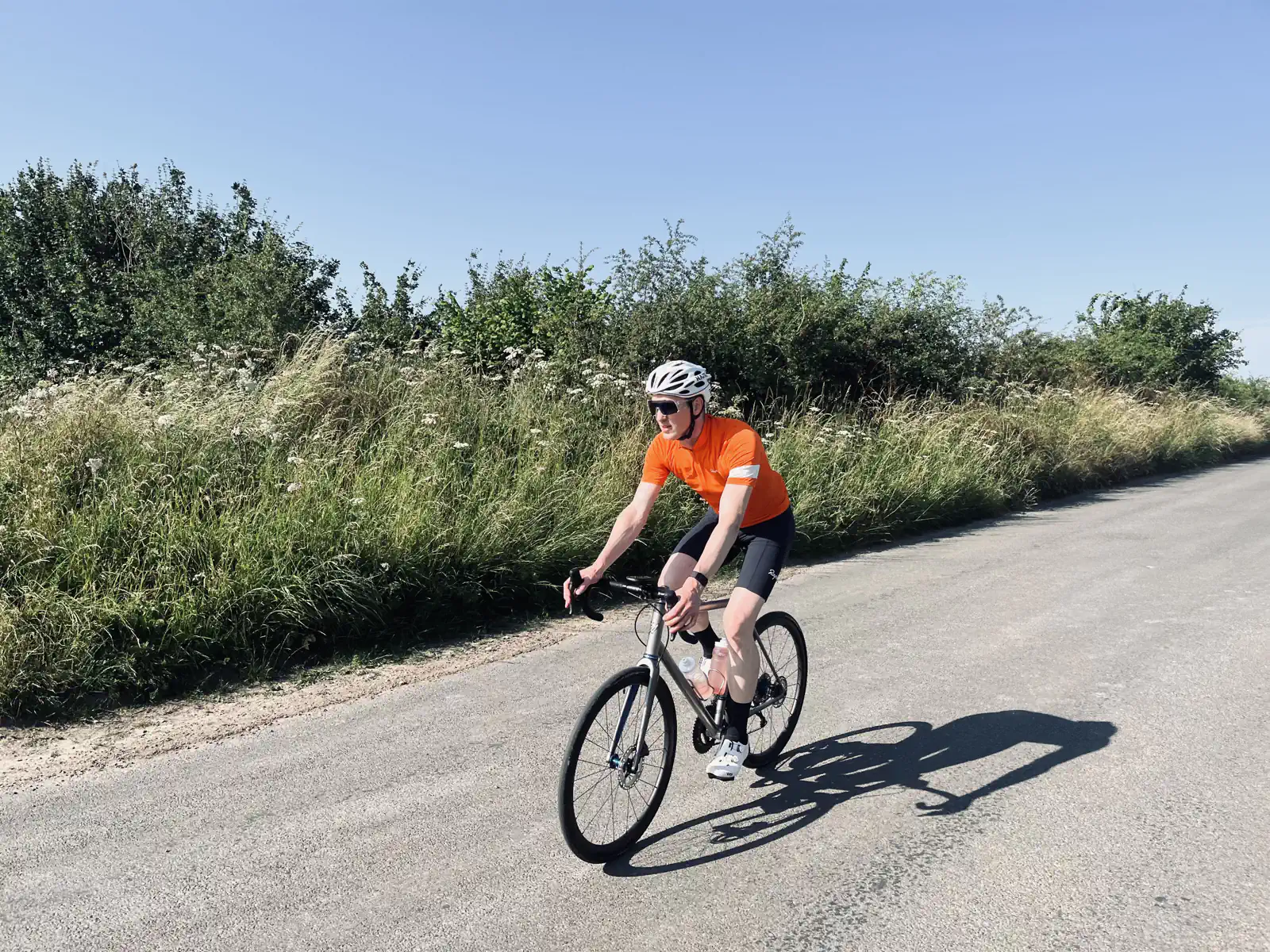 Cyclist in orange jersey riding on a sunny country road