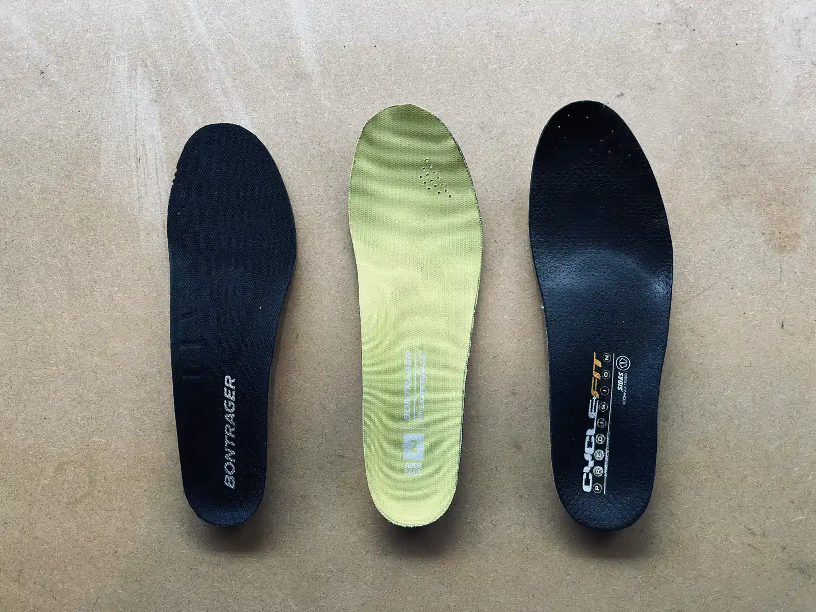 Three different types of shoe insoles laid out side by side on a surface.
