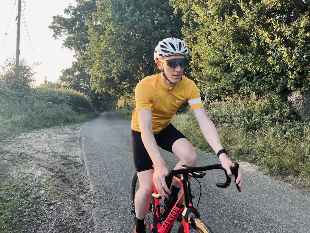 A cyclist in yellow jersey and helmet riding on a rural road.