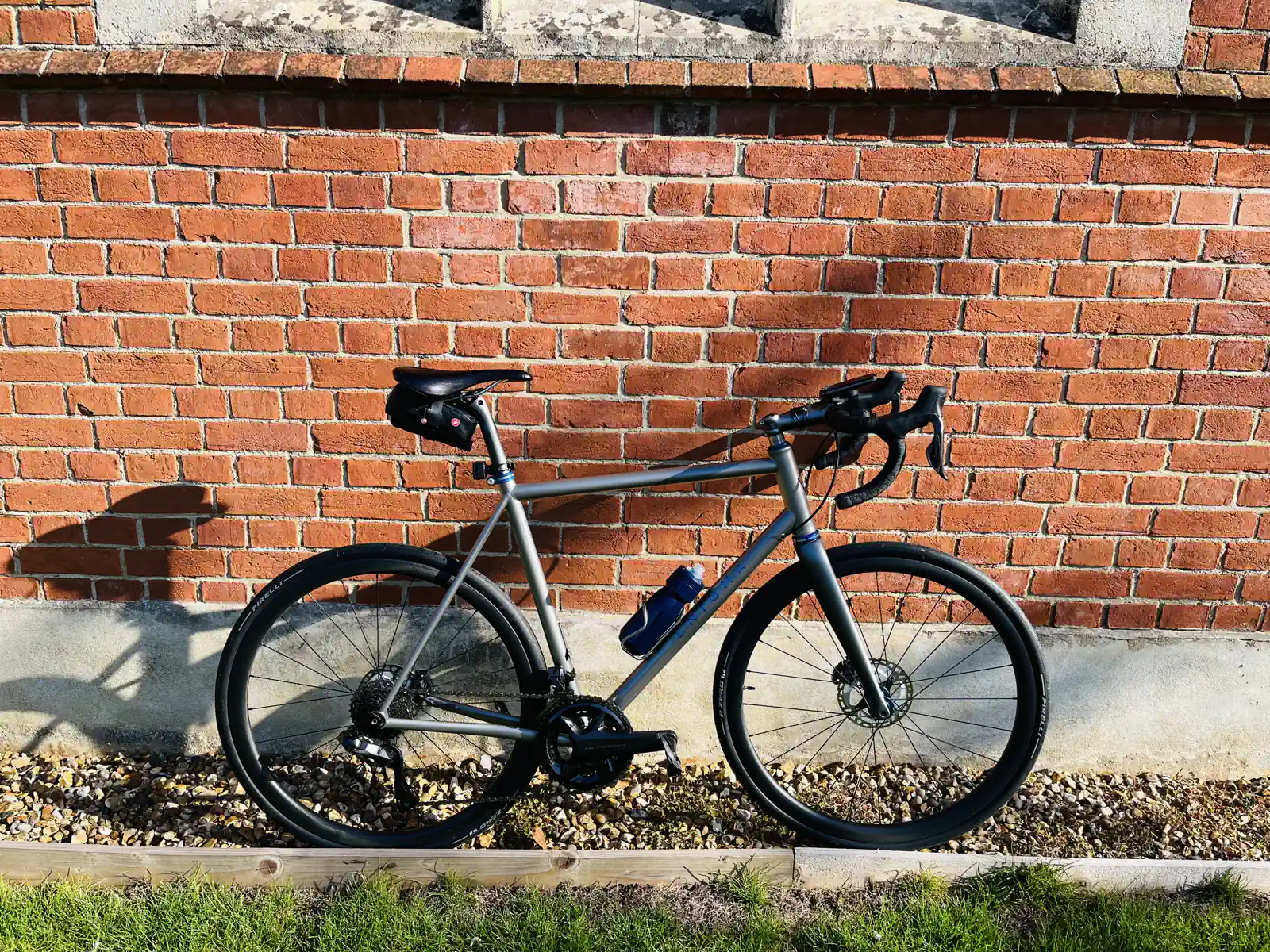 Road bicycle leaning against a brick wall in the sunlight.
