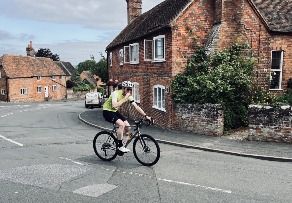 So there's this person, dressed in a bright green top and wearing a helmet, biking down a street with red brick buildings. They're pedaling with one hand on the bike and chatting on the phone with the other.