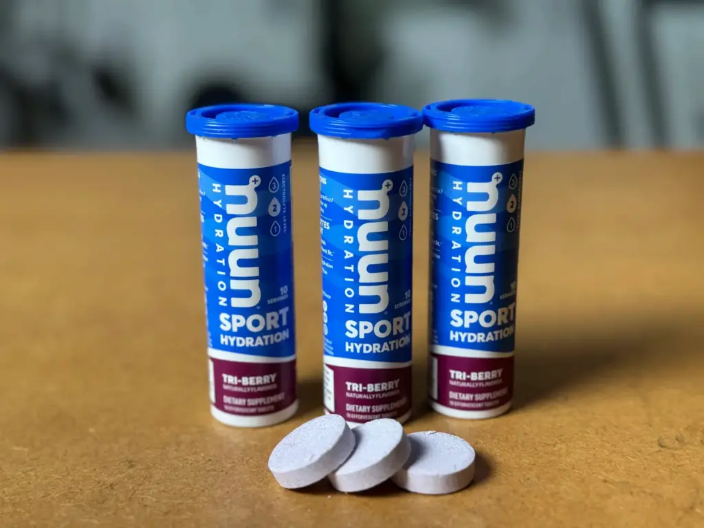 Three tubes of Nuun Sport Hydration tablets in that tasty Tri-Berry flavor are chilling on a table, with a few tablets laid out in front.